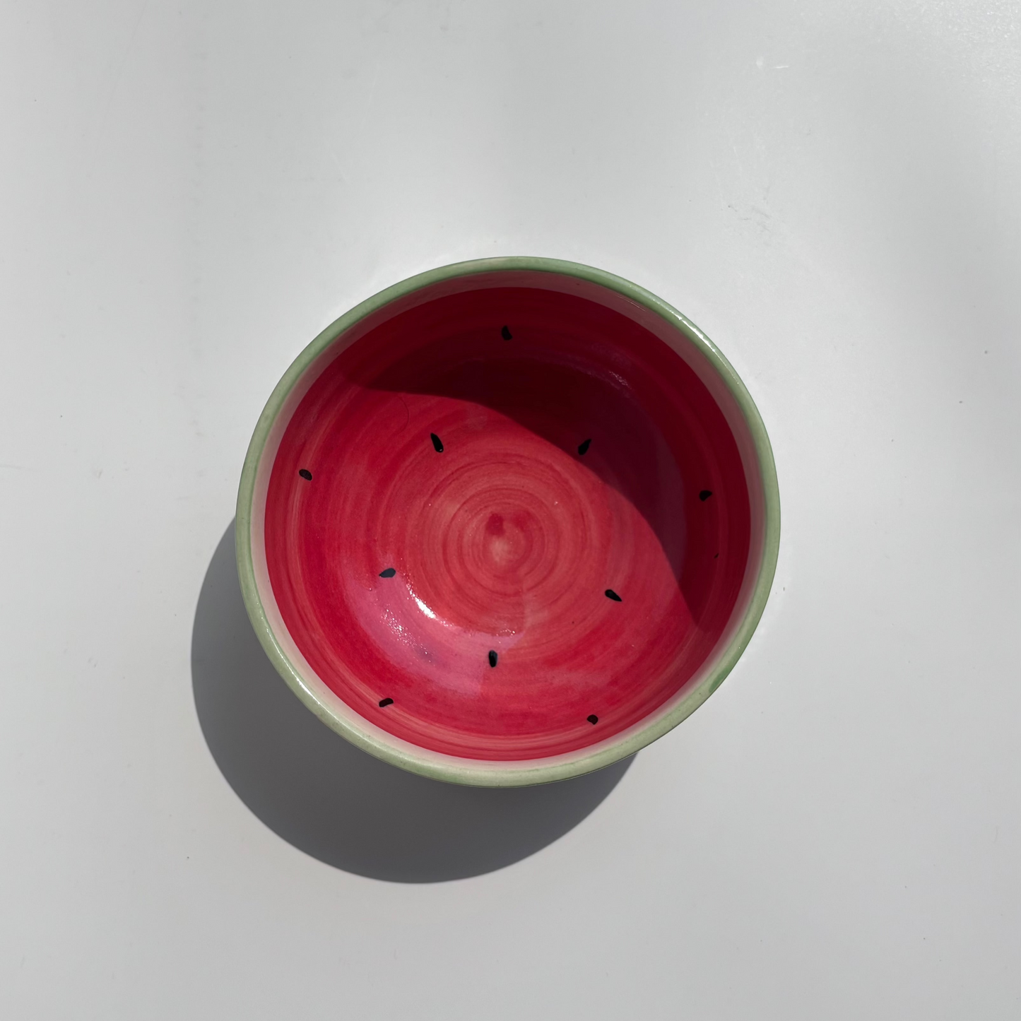 Red ceramic bowl with green rim on a white background