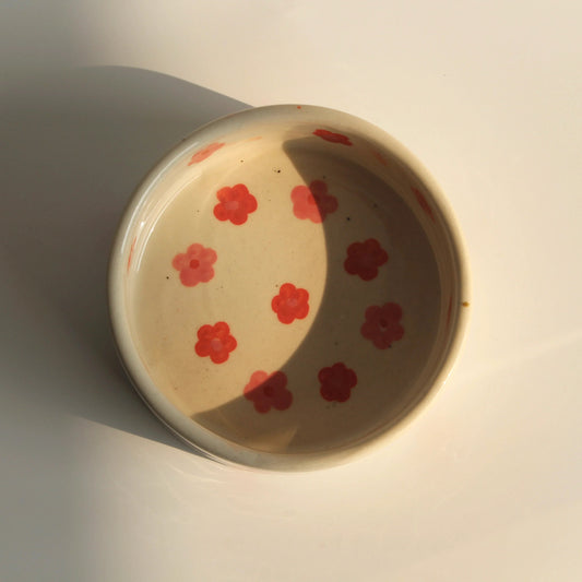 Ceramic bowl with red floral patterns on a white background
