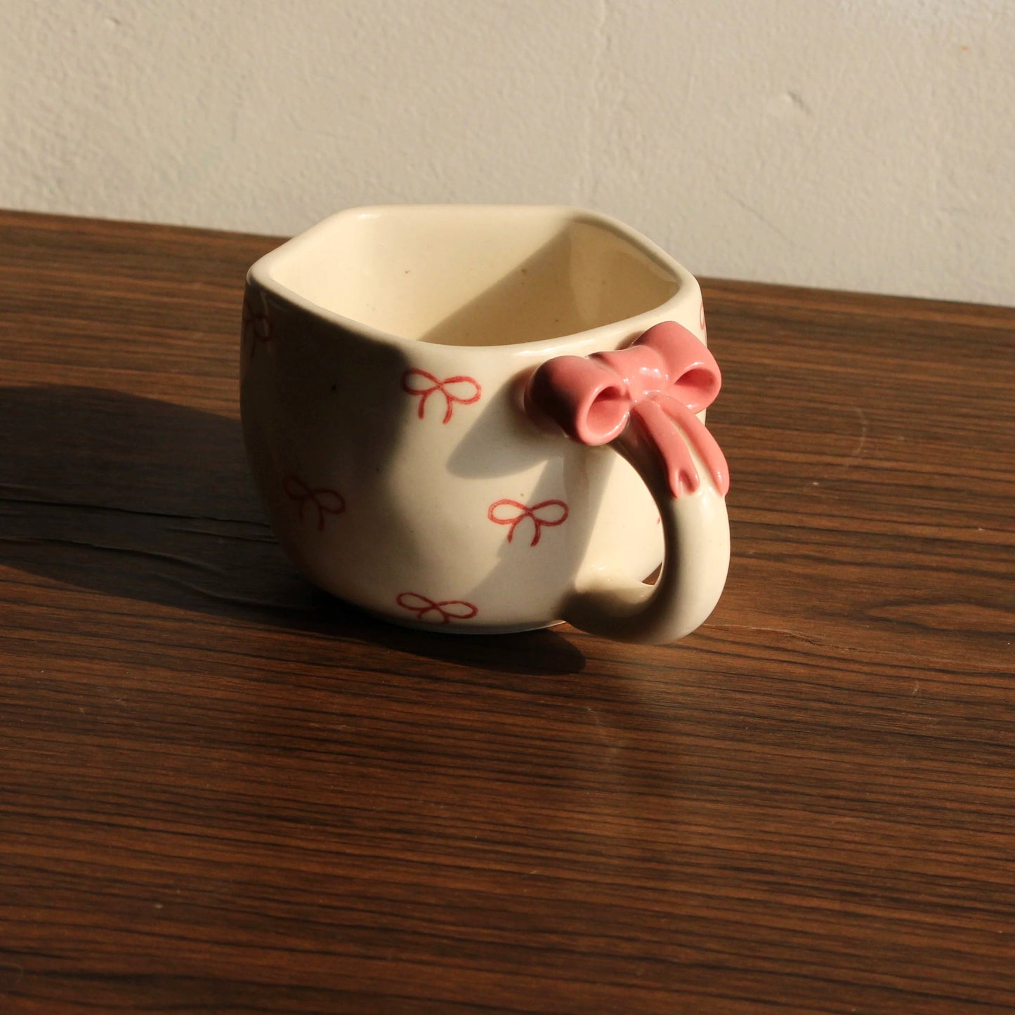 Ceramic mug with pink bow on a wooden surface