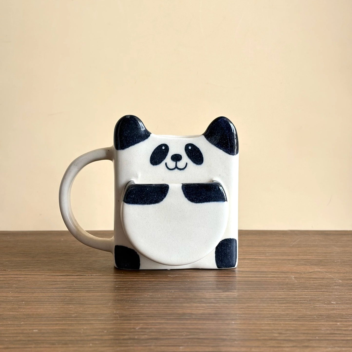 Panda mug on a wooden surface with a beige background