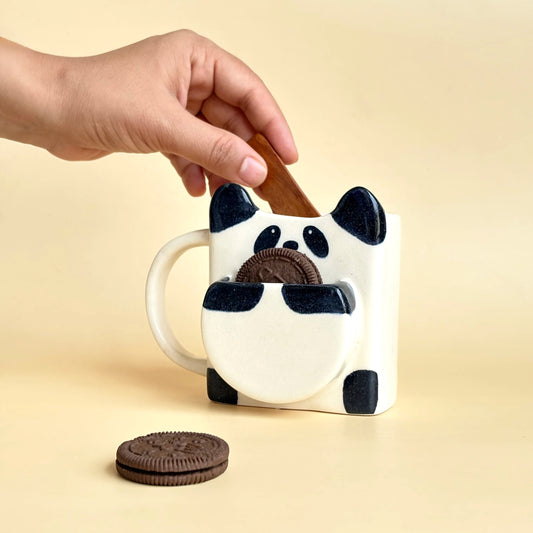 Ceramic mug shaped like a panda with Oreo cookies on a beige background
