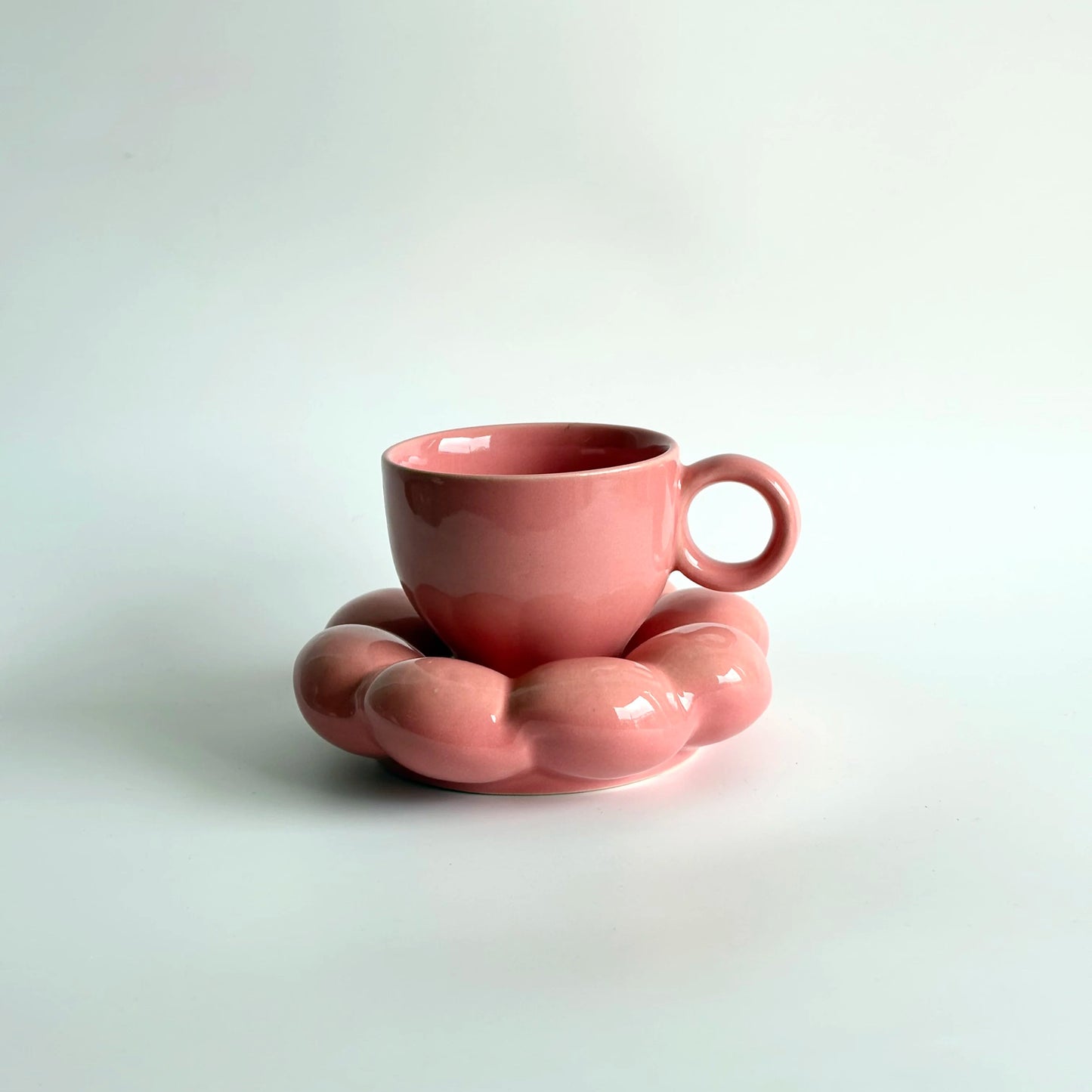 Pink ceramic cup on a matching pink ceramic coaster against a light gray background