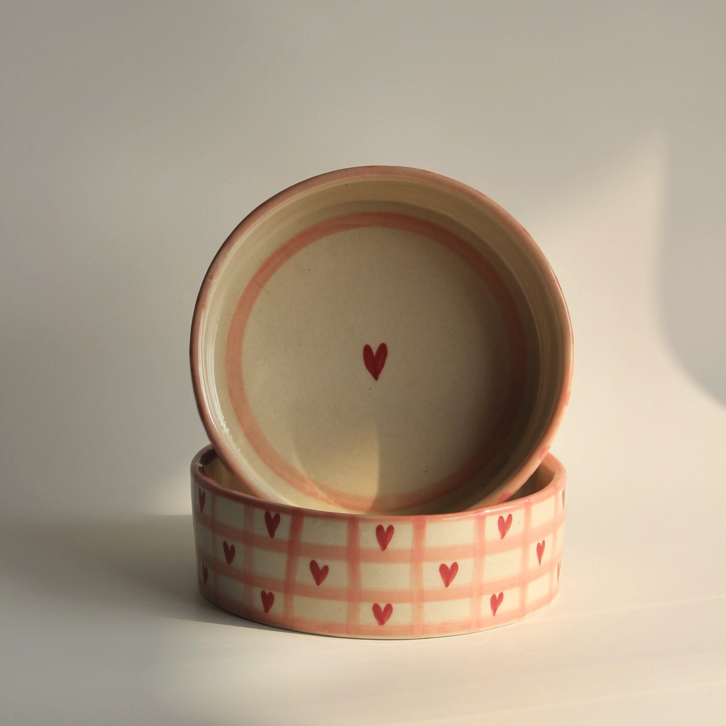 Two ceramic bowls with heart patterns on a light background