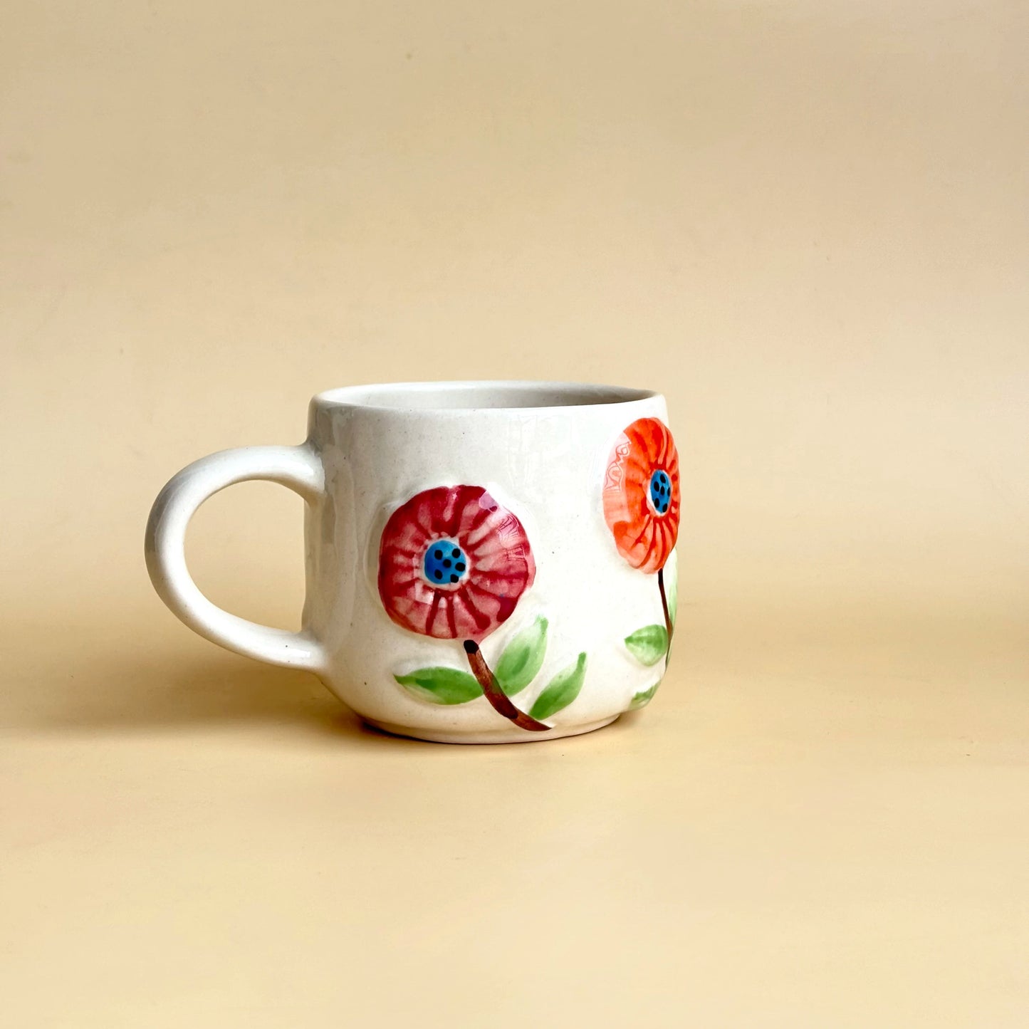 White mug with floral designs on a beige background