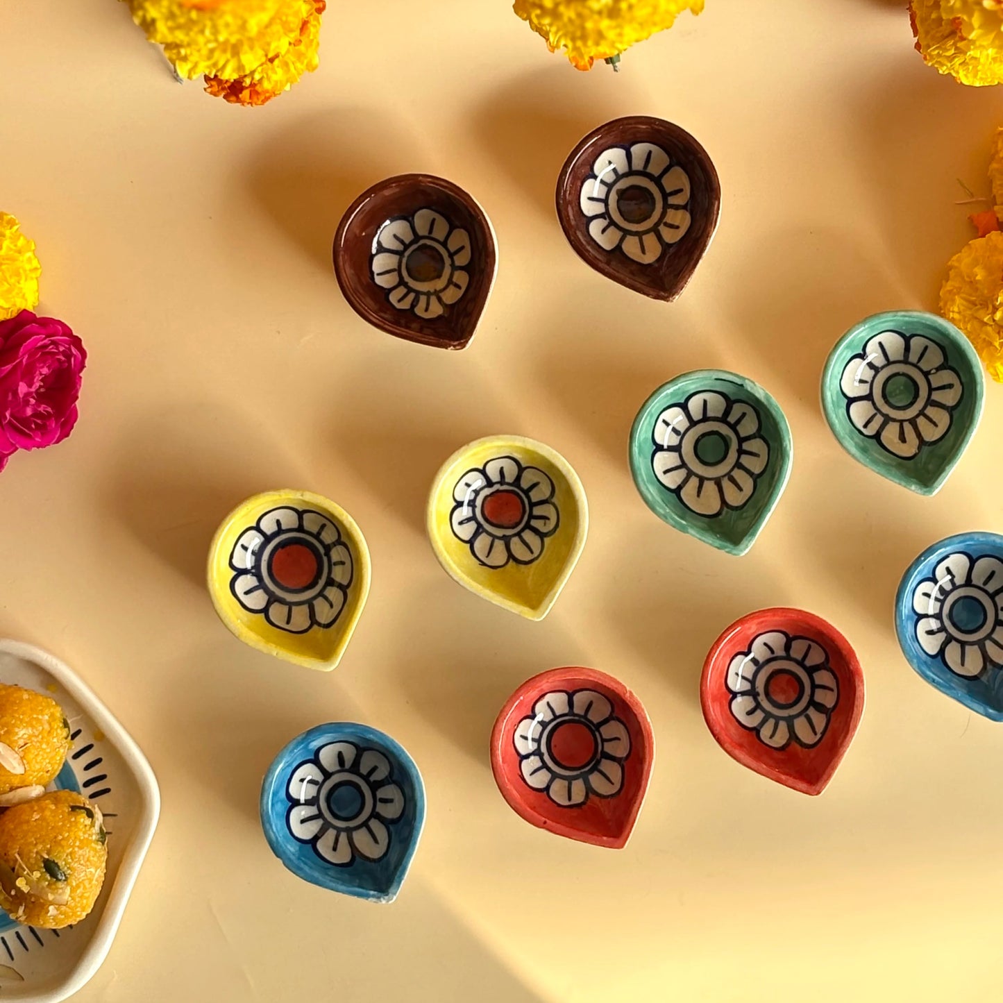 Colorful flower-shaped candies on a beige surface with yellow flowers in the background.