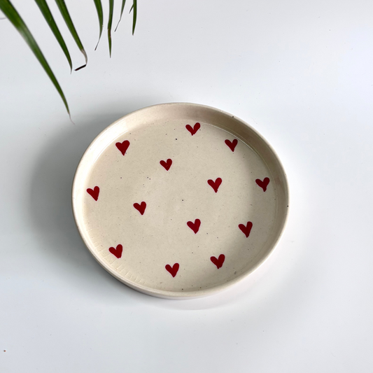 Ceramic plate with red heart patterns on a light gray background