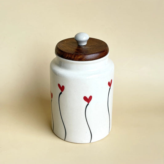 Ceramic jar with wooden lid and red floral design on a beige background