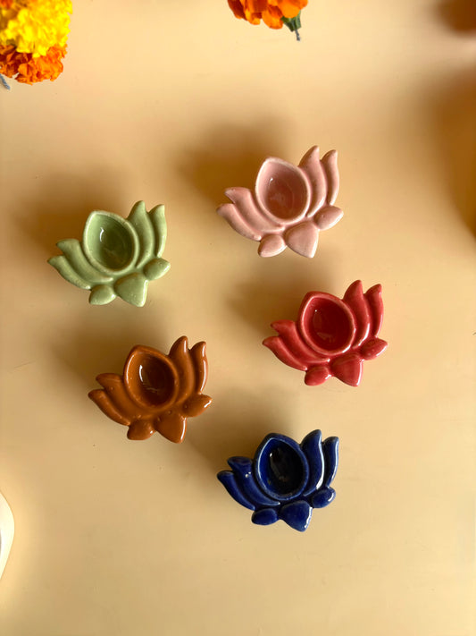 Five ceramic lotus flower-shaped objects in different colors on a beige background.