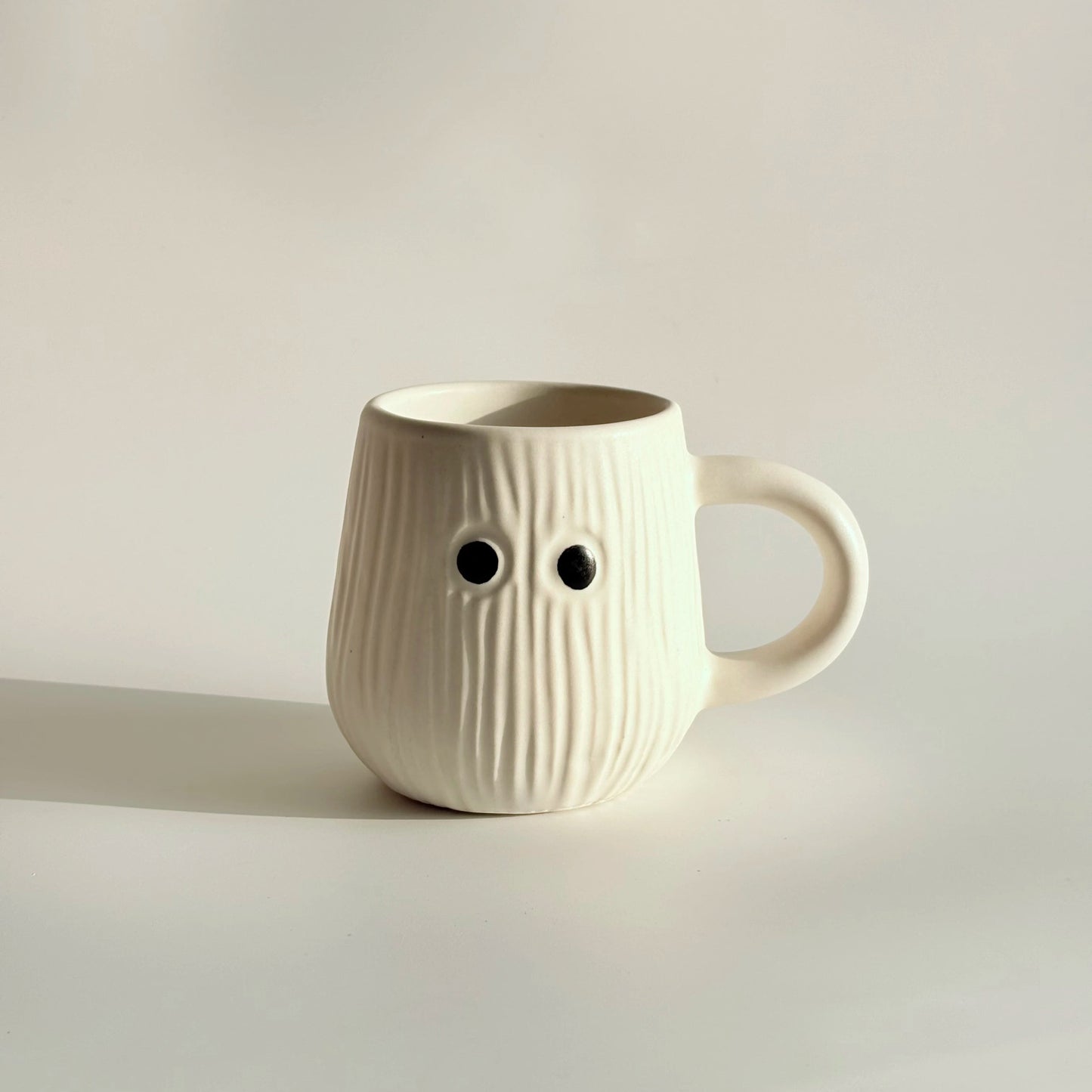 White ceramic mug with face-like design on a light background