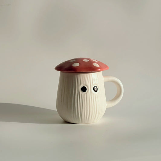 Mushroom-shaped mug with a red cap and black eyes on a plain background