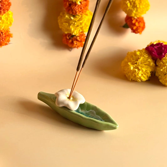 Incense stick with a leaf holder on a beige background with decorative flowers.