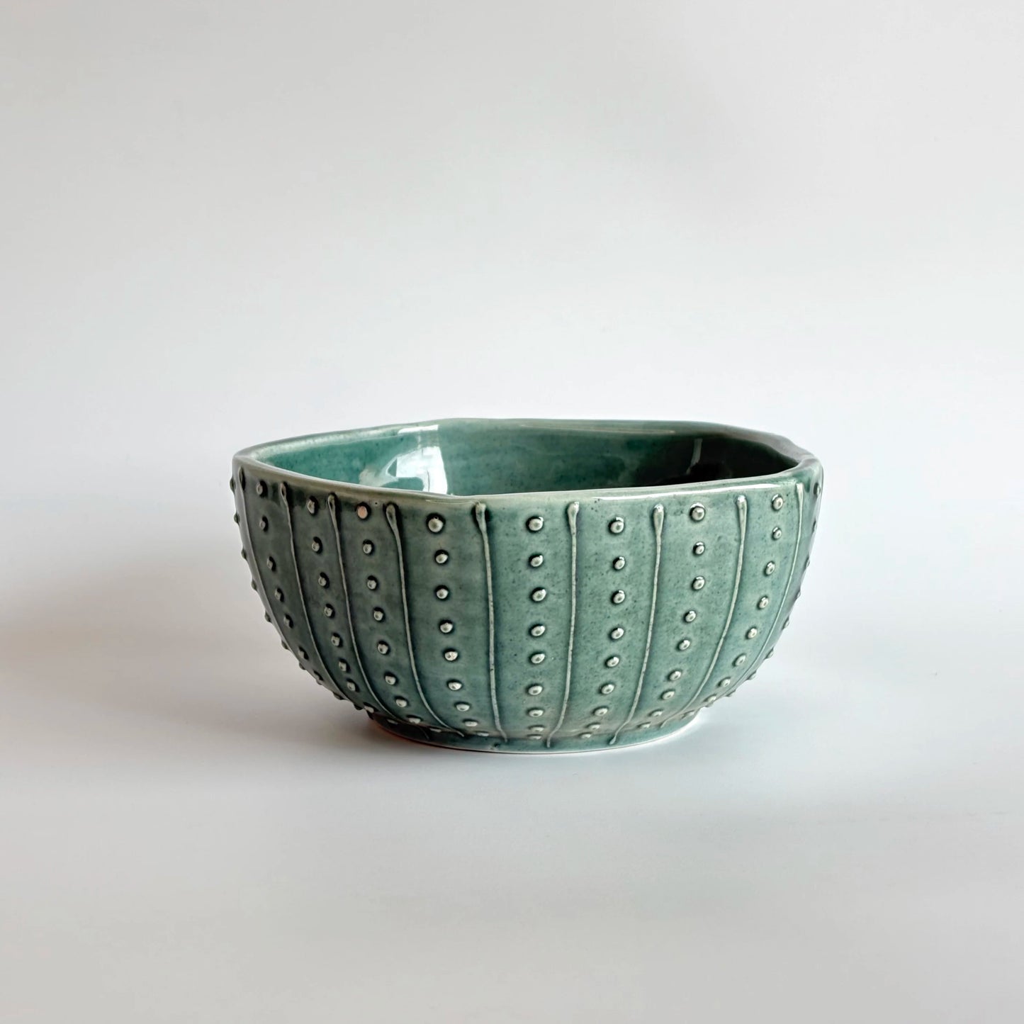 Green ceramic bowl with textured surface on a white background
