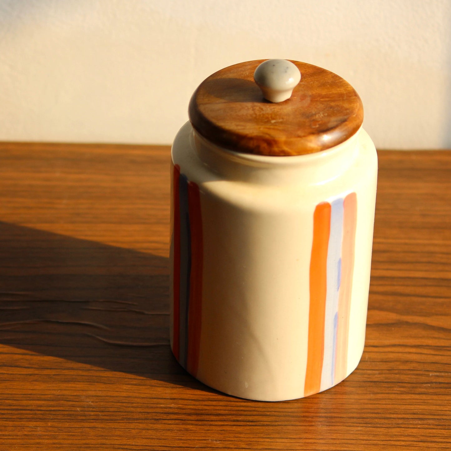 Ceramic jar with a wooden lid on a wooden surface