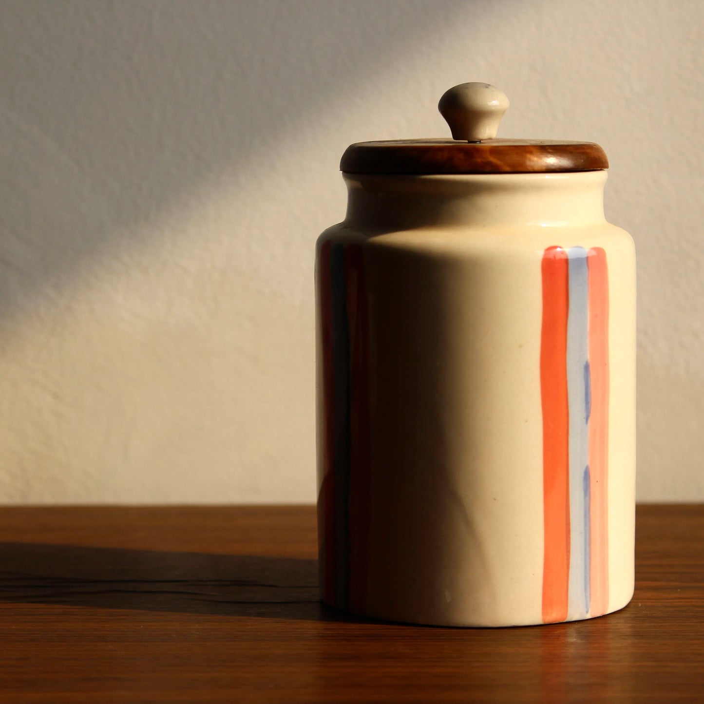 Ceramic jar with striped design on a wooden surface