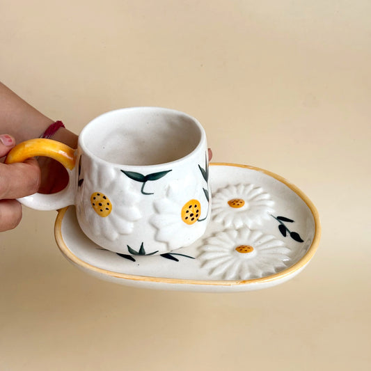 Ceramic cup with floral design held by a hand on a beige background
