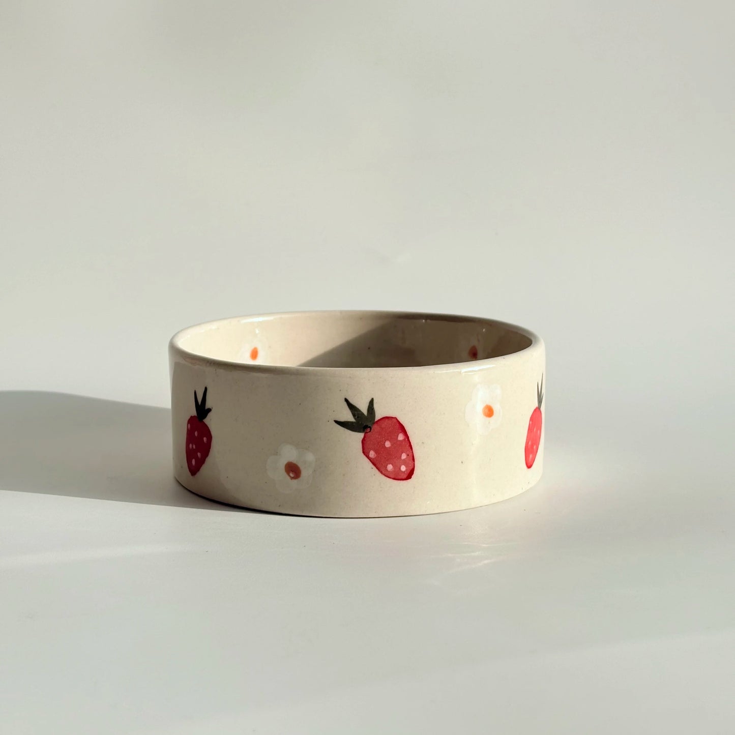 Small ceramic bowl with strawberry pattern on a white background