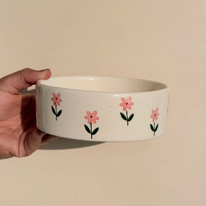 Ceramic bowl with floral design held by a hand against a beige background