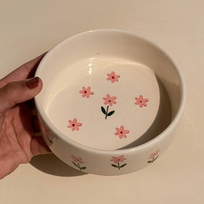 White ceramic bowl with pink floral designs held by a hand on a light background