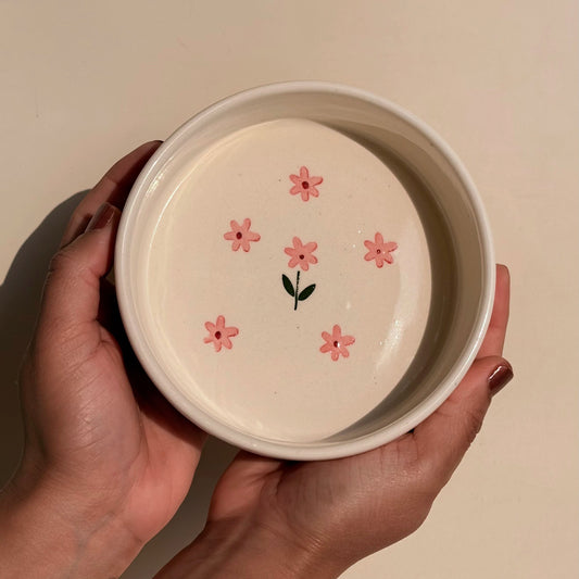 Person holding ceramic bowl with floral design on a beige background