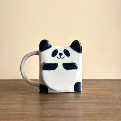 Panda mug on a wooden surface with a beige background