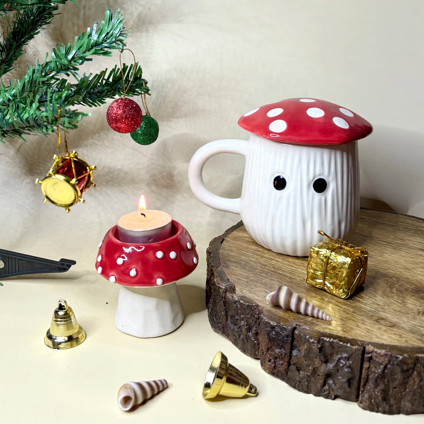 Mushroom-shaped mug and candle holder on a wooden surface with Christmas decorations.