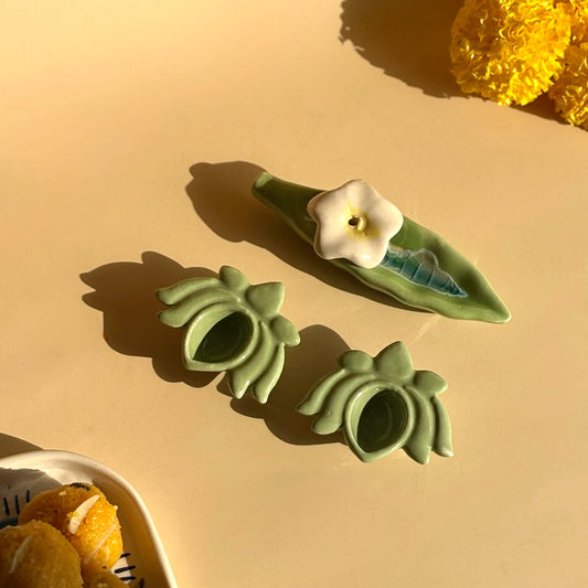 Green ceramic flower pots on a beige surface with yellow flowers in the background
