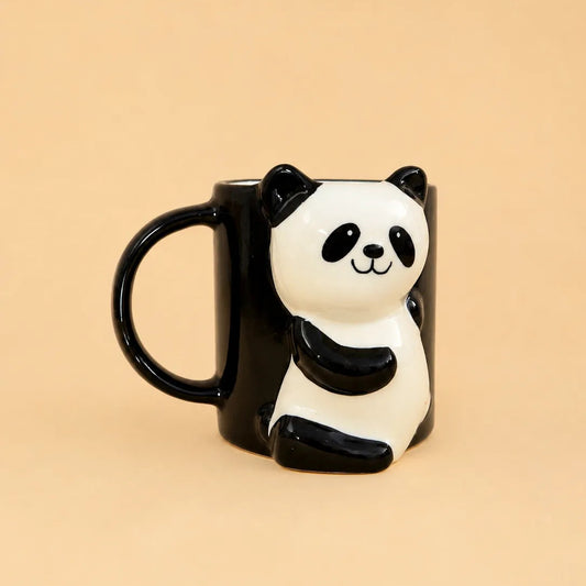 A black ceramic mug shaped like a 3D panda sitting on the side, set against a solid beige background.