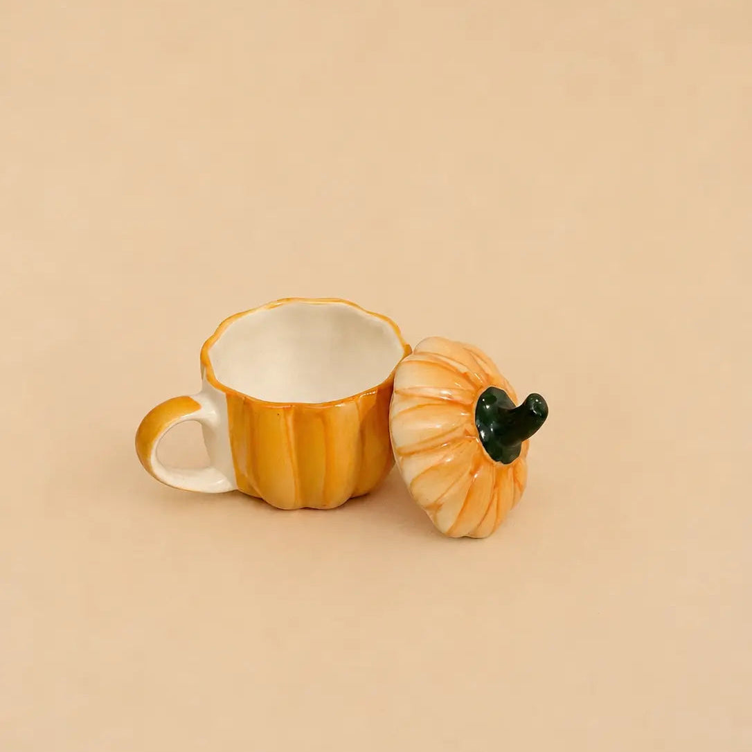 Pumpkin-shaped mug with a lid on a beige background