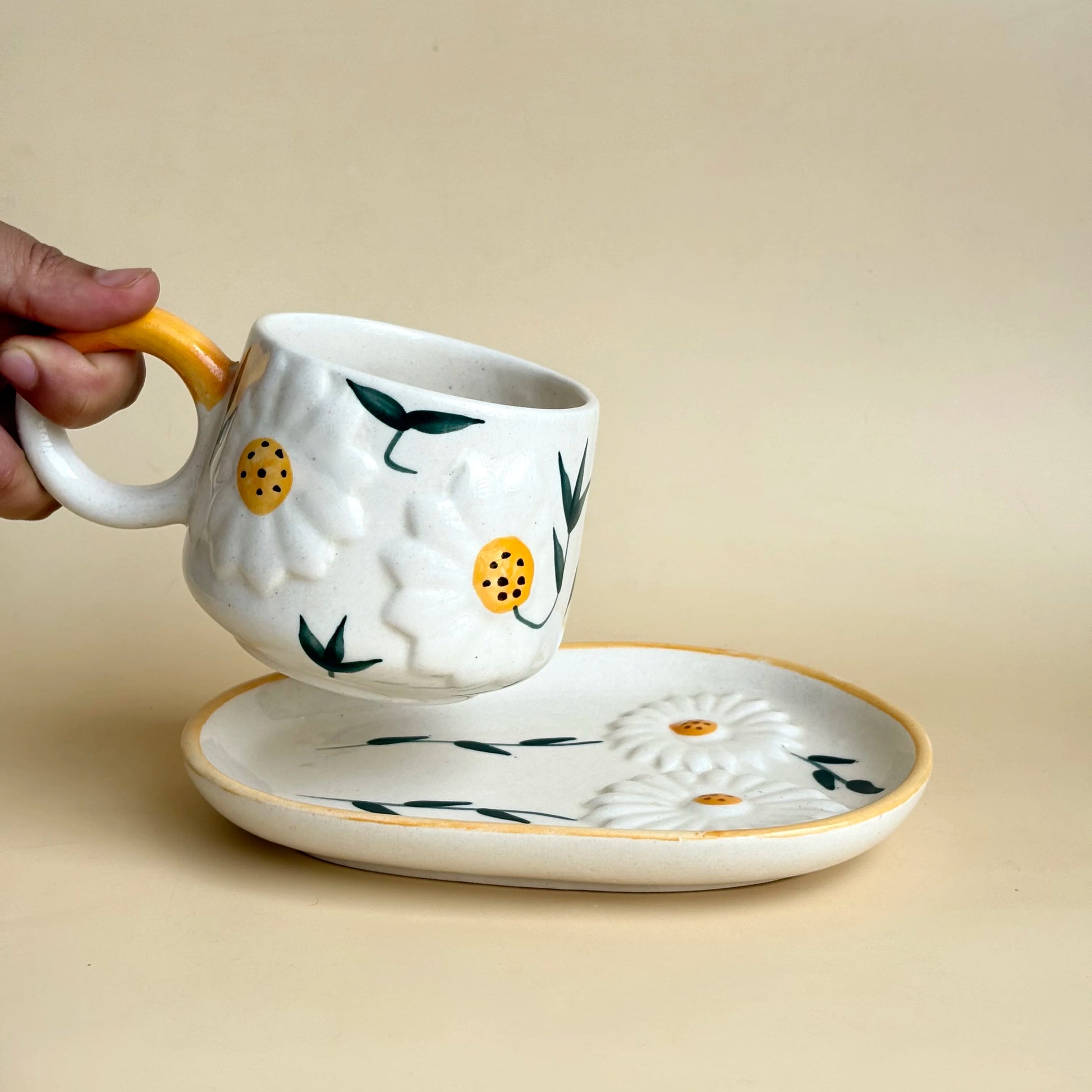 Ceramic mug and saucer with floral design on a beige background