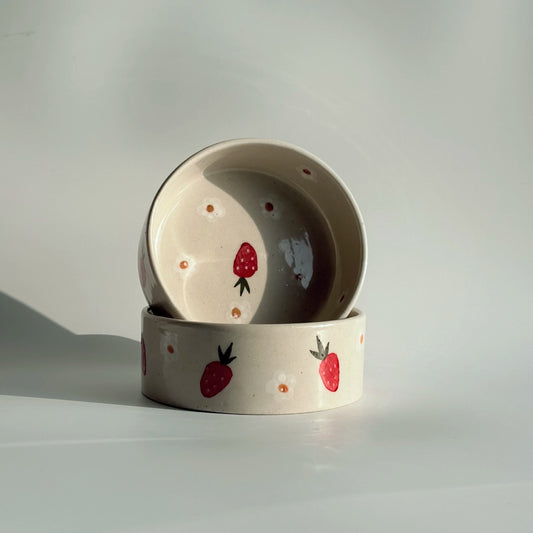 Two ceramic bowls with strawberry design on a light gray background