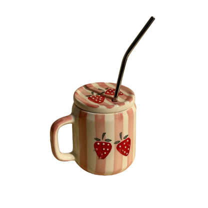 A ceramic mug with a lid, decorated with pink and white vertical stripes and red strawberry motifs, featuring a black metal straw, set against a warm beige background with a soft shadow.